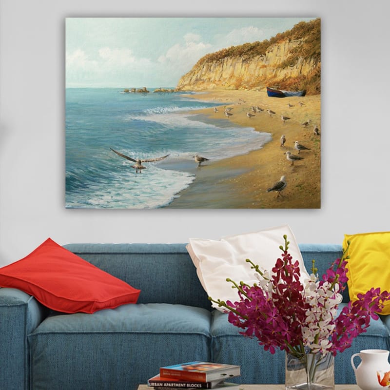 Lærred 70x100 cm - Strandscene med fugle, der flyver og går langs vandet, omgivet af klipper og en båd på kysten - Blå / Beige / Grøn - Boligtilbehør - Billeder & kunst - Billeder på lærred
