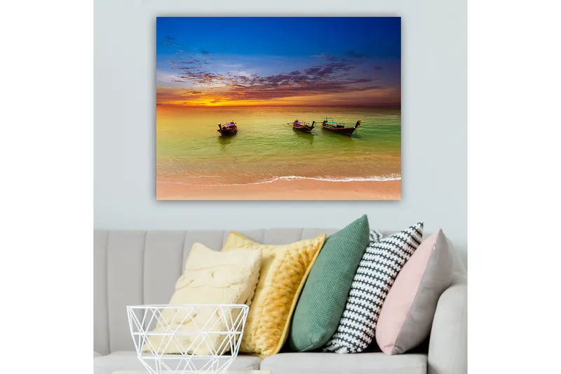 Lærred 70x100 cm - Tre traditionelle både liggende på en strand under en farverig solnedgang, Blå / Orange / Grøn