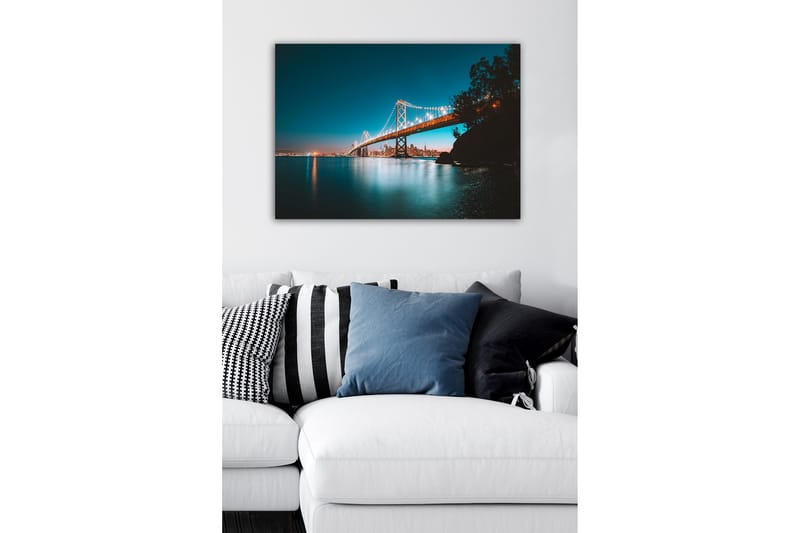 Lærredsbillede - Oplyst bro over en stille vandoverflade med byens skyline i baggrunden - Blå / Orange / Sort - Boligtilbehør - Billeder & kunst - Billeder på lærred