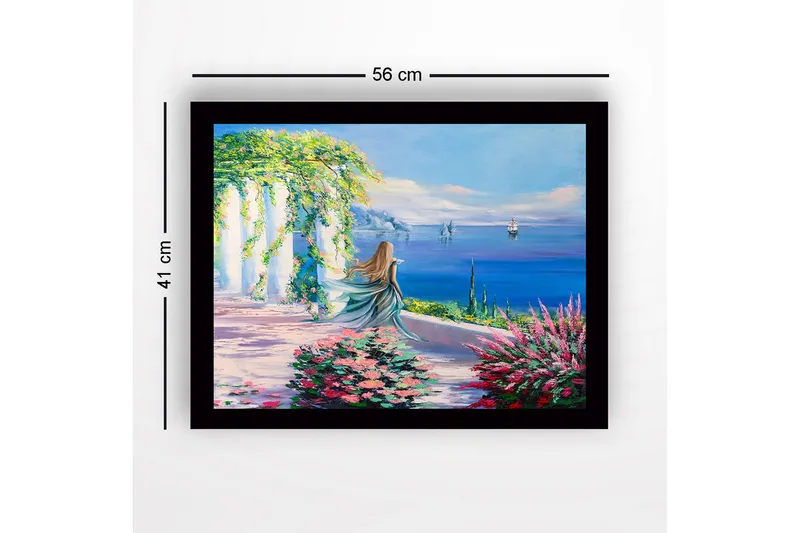 Indrammet lærred i træ - 41x56 cm - Kvinde i blå kjole kigger ud over havet med blomster i forgrunden - Blå / Grøn / Lyserød - Boligtilbehør - Billeder & kunst