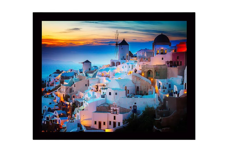 Indrammet trælærredstryk - 41x56 cm - Smuk udsigt over en græsk landsby med hvide huse og en vindmølle ved solnedgang, Hvid / Blå / Orange